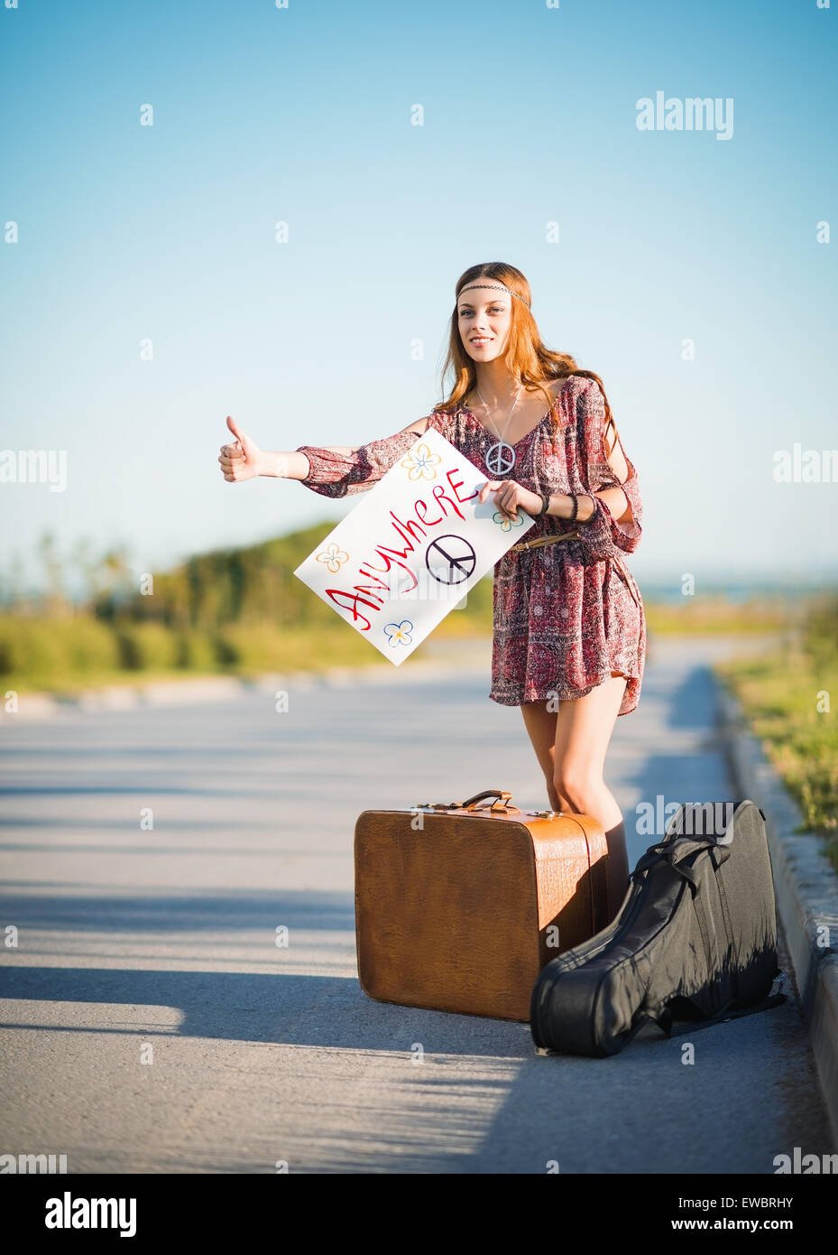 Portrait of a lovely young hippie girl hitchhiking on the road Stock Photo