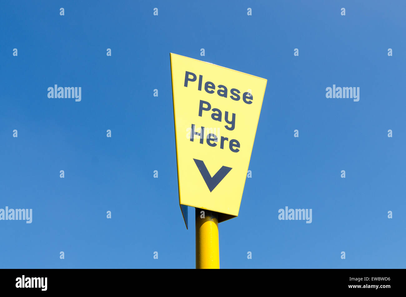 Please Pay Here blue and yellow car park sign against blue sky Stock Photo