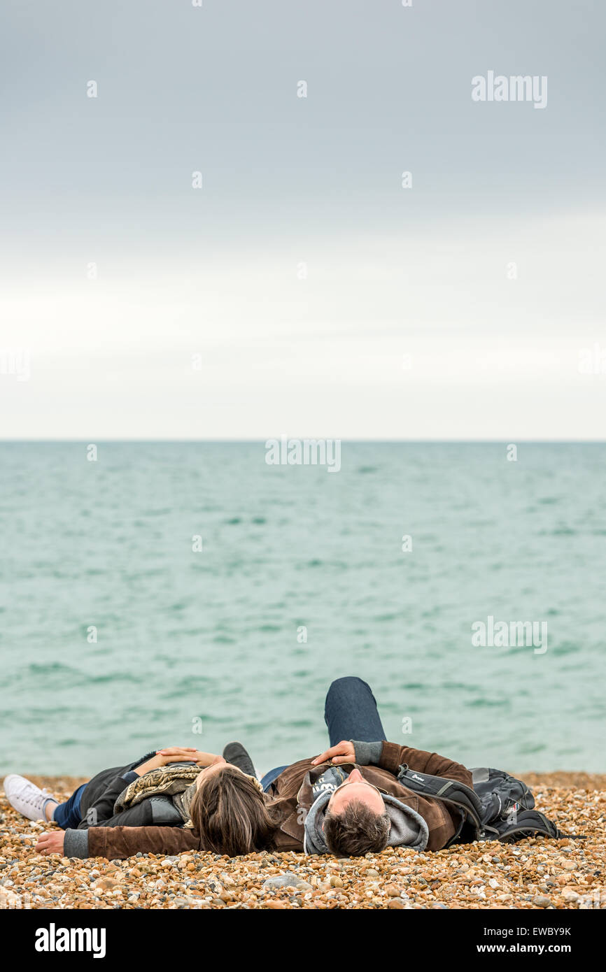 A couple relax on the beach at the seafront in Brighton, East Sussex, England. Stock Photo