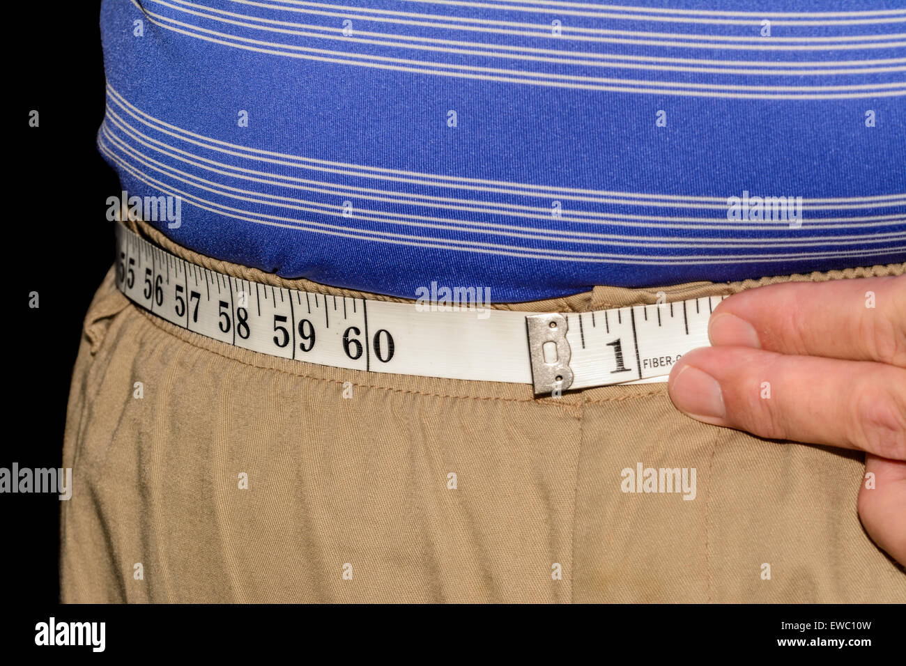 Obese man measuring his waist with a tape measure. Stock Photo