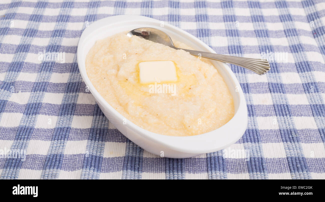 A bowl of white corn grits on a blue plaid placemat Stock Photo