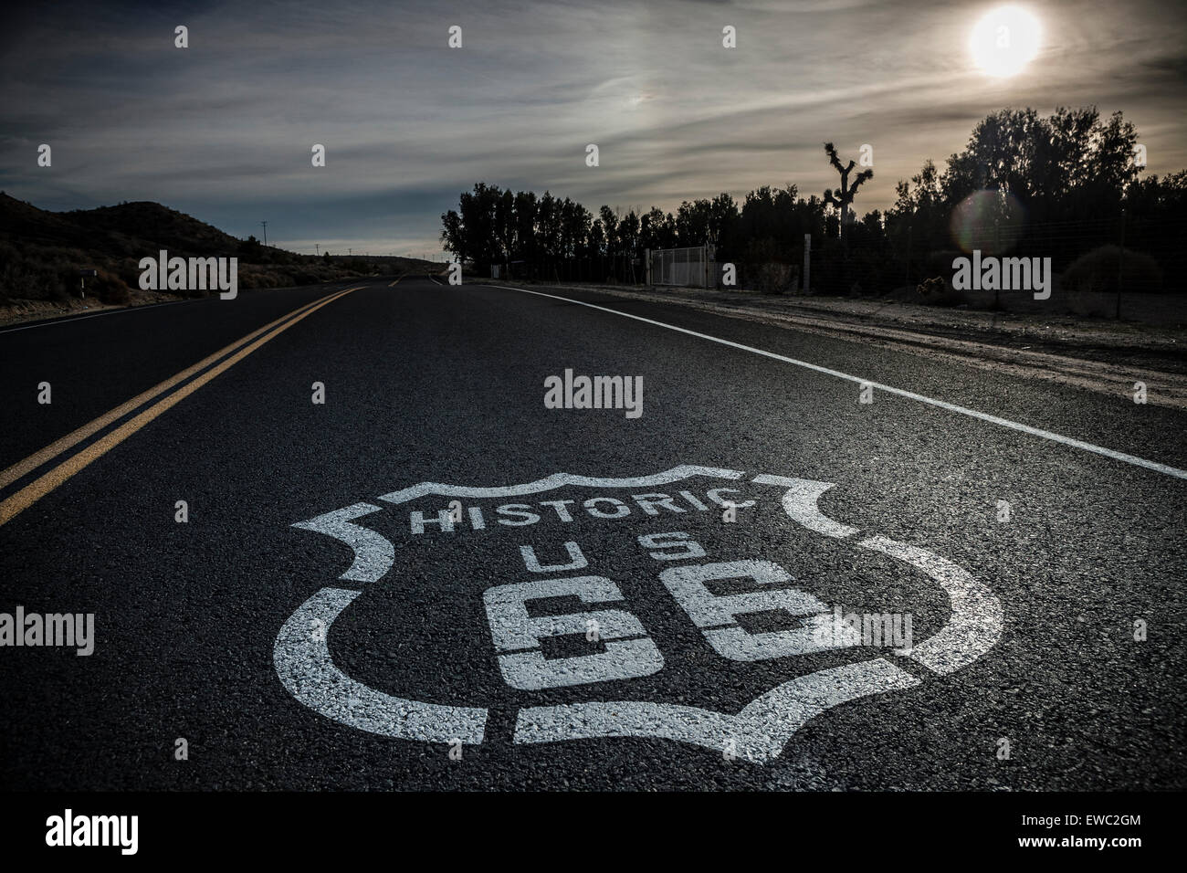 Classic image Historic Route 66 sign painted on highway. Dark and moody clouds, hazy sunshine Stock Photo