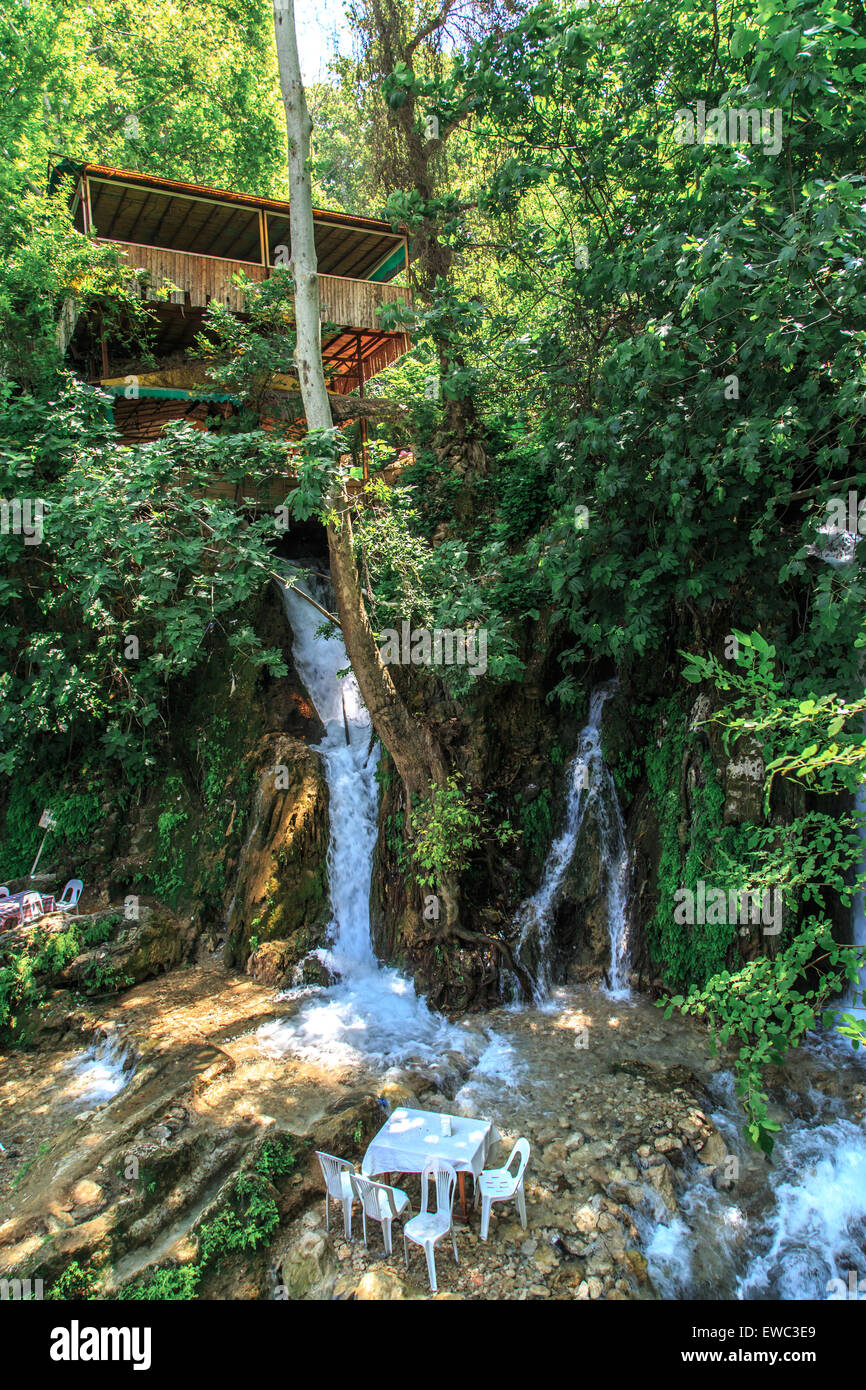 Bottom view of flowing waterfall and observation terrace among trees. Stock Photo