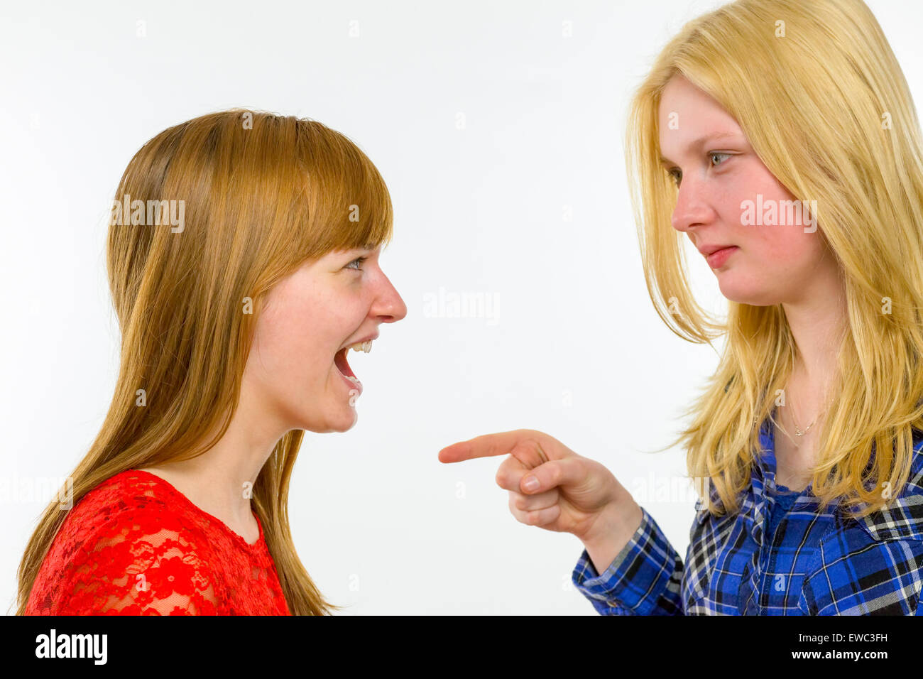 Blonde caucasian girl pointing at red haired girlfriend isolated on white background Stock Photo