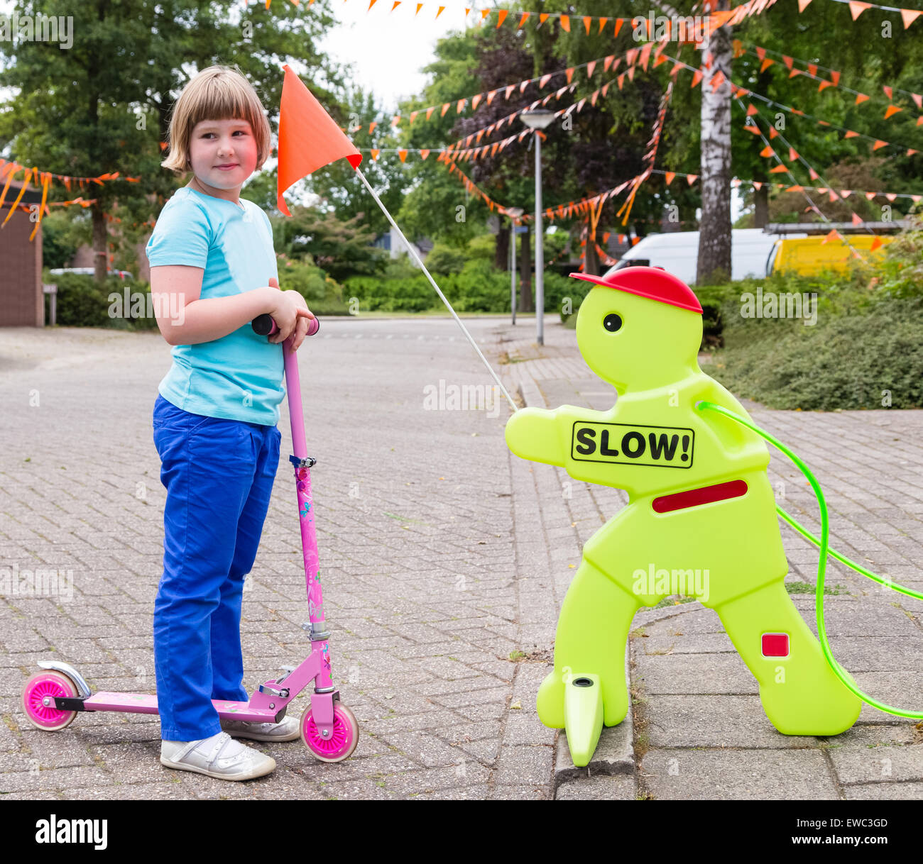 Young caucasian girl on pink  scooter with safety figurine in street Stock Photo