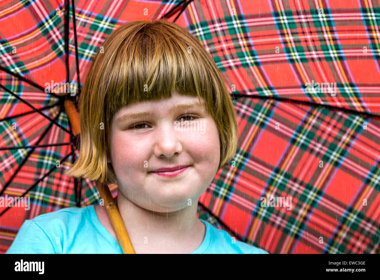 Young blonde dutch girl under red umbrella in rain Stock Photo
