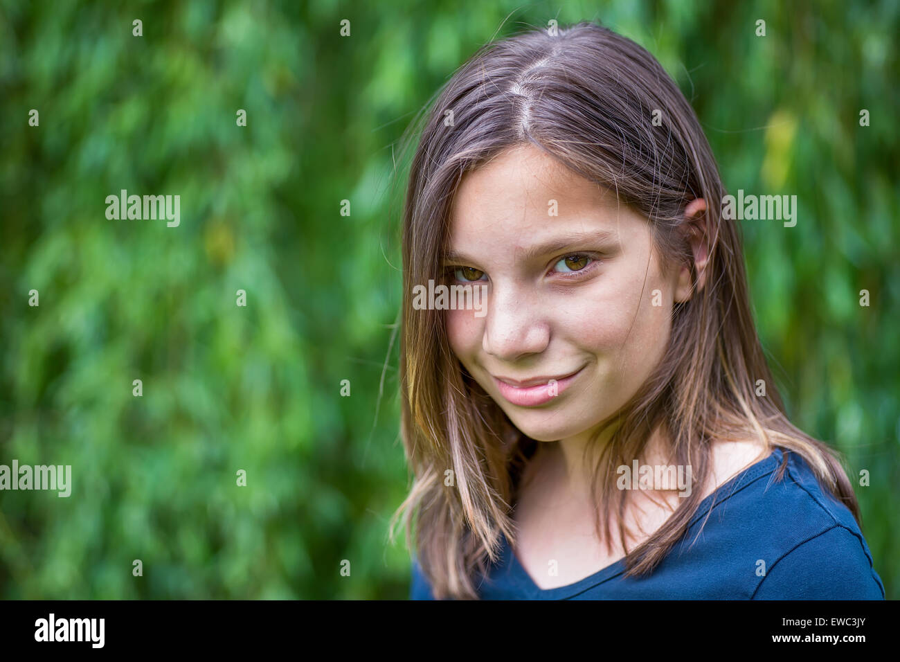 Portrait of caucasian teenage girl in front of green willow Stock Photo