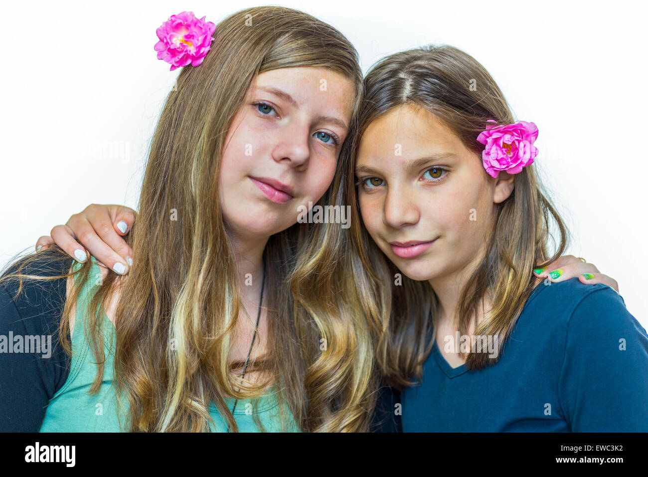 Two caucasian teenage sisters wearing pink roses embracing each other Stock Photo