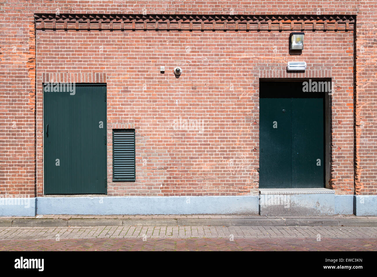 Old brick wall with green doors and street Stock Photo