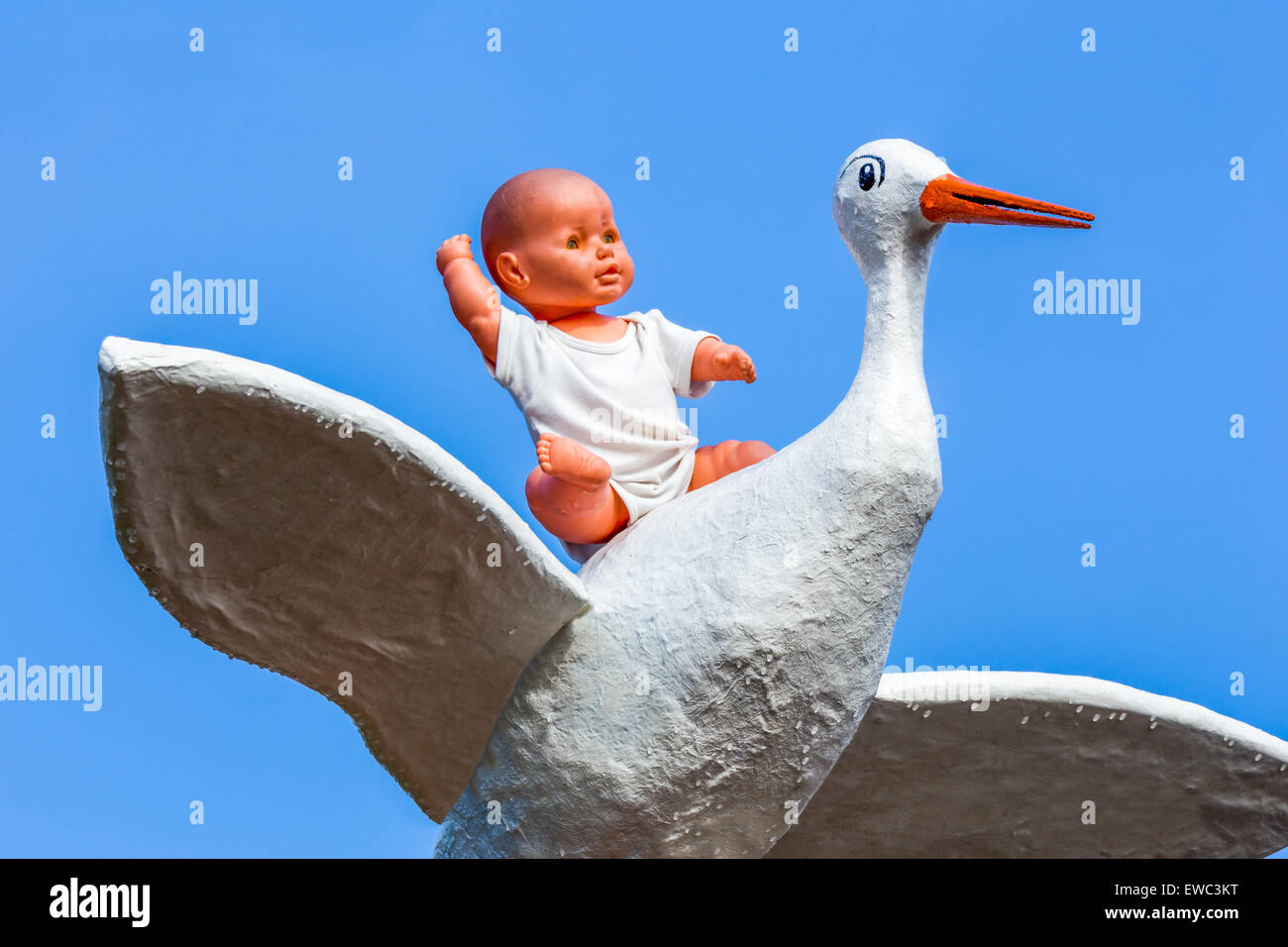 Baby doll sitting on stork with blue sky Stock Photo