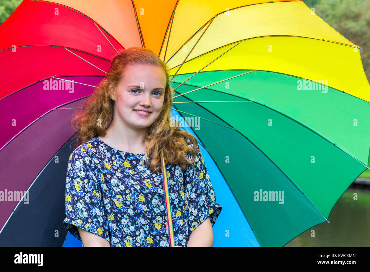 Caucasian teenage girl outdoors under umbrella with various colors Stock Photo