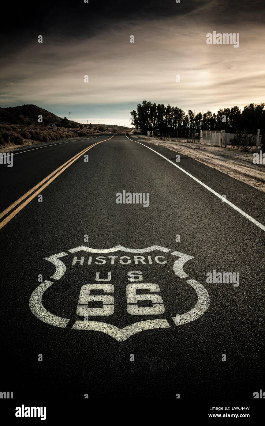 Classic image Historic Route 66 sign painted on highway. Dark and moody clouds, hazy sunshine Stock Photo