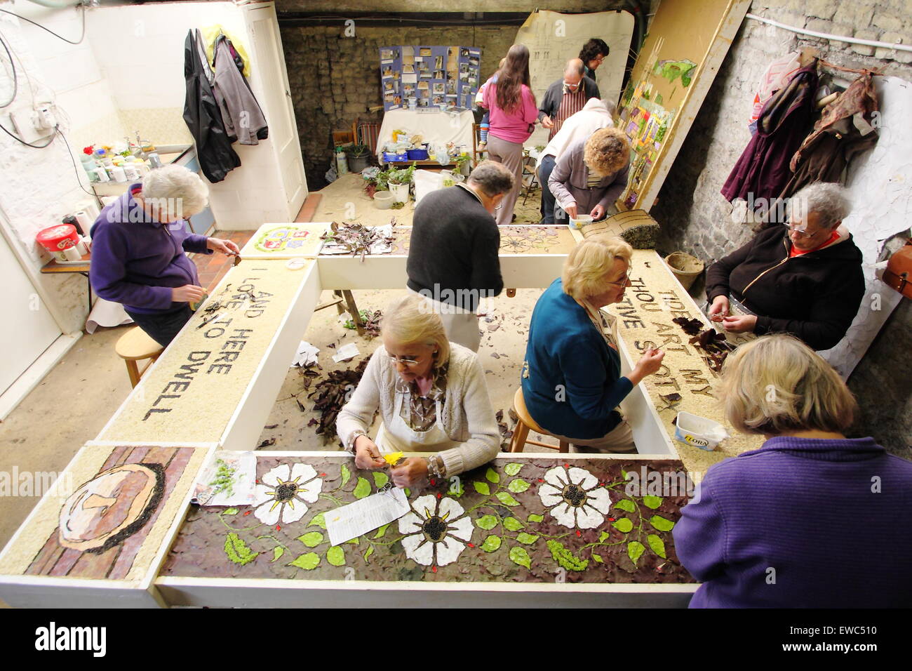 Volunteers prepare a well dressing with natural materials ahead of its display in Tideswell village, Peak District Derbyshire UK Stock Photo