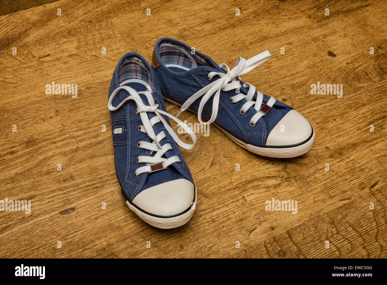 Pair of blue canvas sneakers are on the yellow wood floor Stock Photo