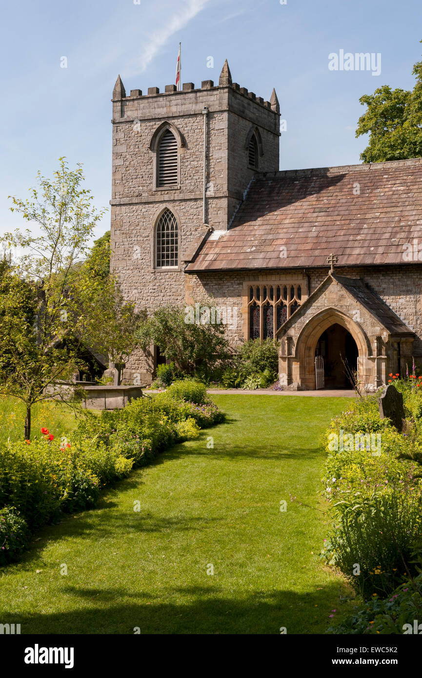 St. Mary's church, Kettlewell, Yorkshire Dales, England, UK. View from beautiful, lush, garden with grass path, meadow flowers, summer sun & blue sky. Stock Photo