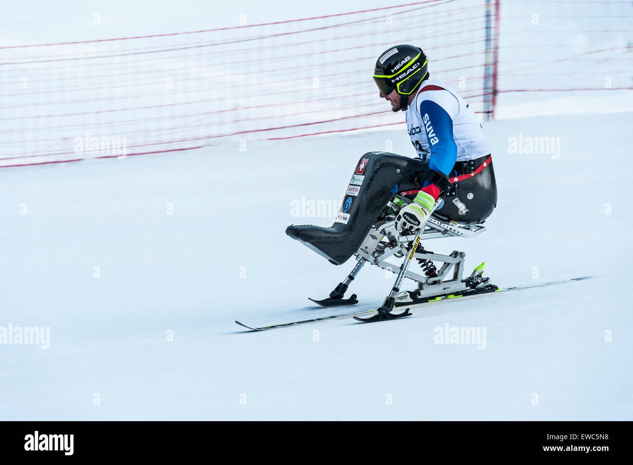 A disabled competitor using specially-adapted ski equipment, racing downhill in a giant slalom race Stock Photo