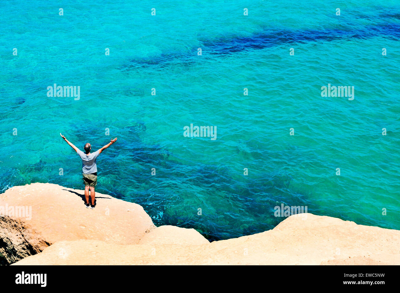 a young man with the arms in the air in front of the ocean, feeling free Stock Photo
