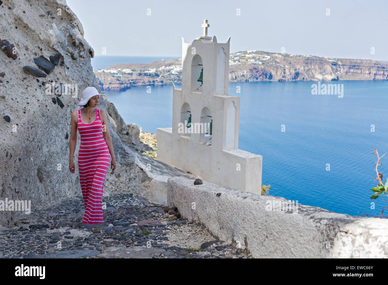 Woman walks up the mountain stairs, at the bottom of the bell tower of the Church. Greece Santorini Stock Photo