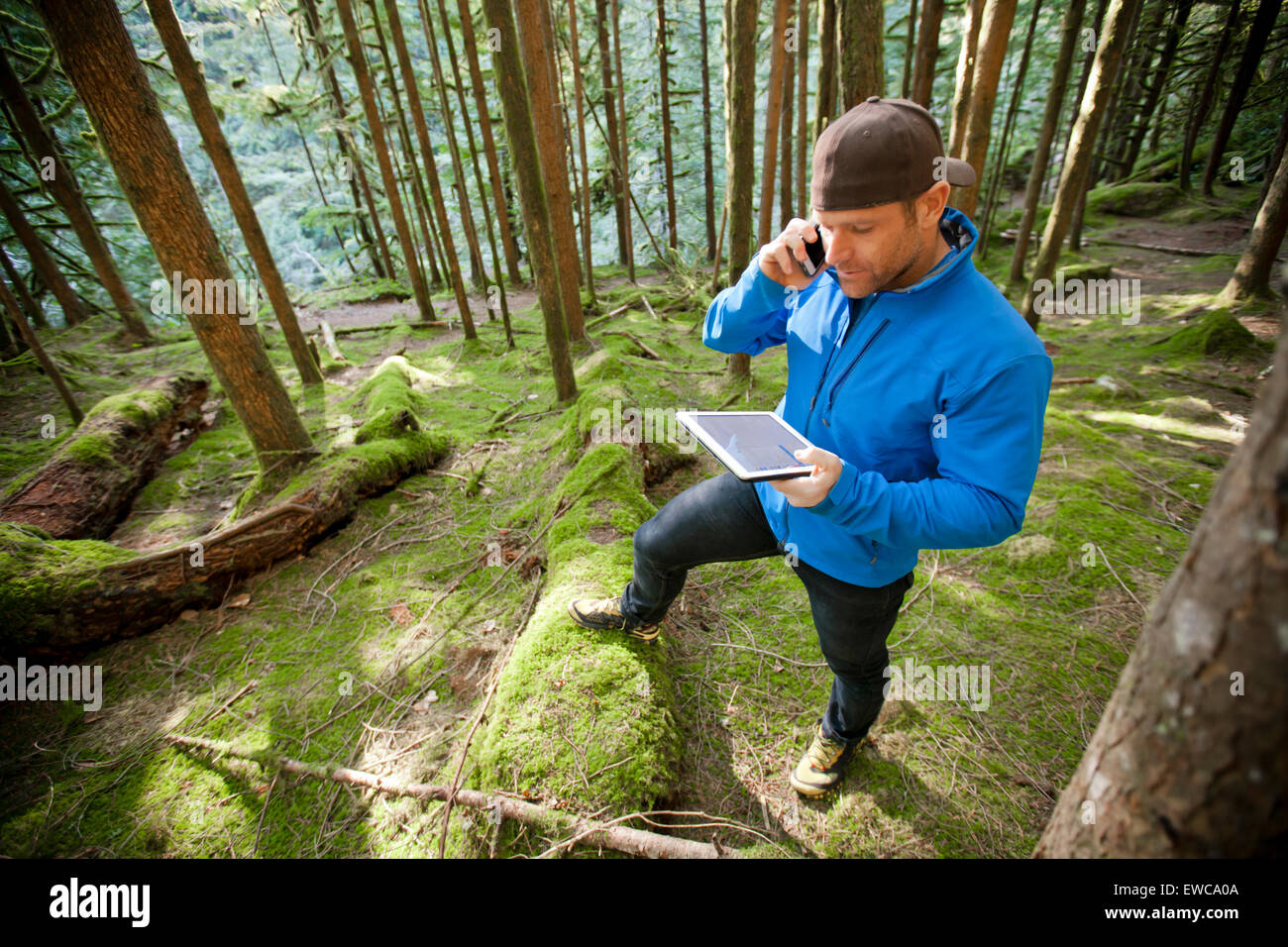 A man talks on phone while working on a tablet. Stock Photo