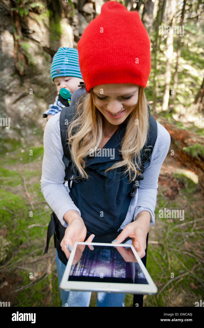 A young mother and her baby look down at a picture on a tablet. Stock Photo