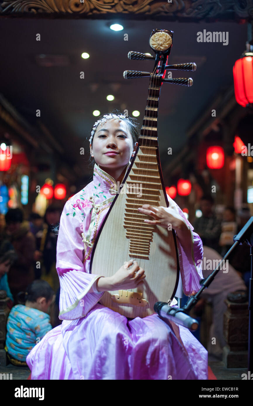Chengdu, China - December 29 2014: Chinese musician girl playing traditional chinese guitar onstage at Chunxifang Chunxilu Stock Photo