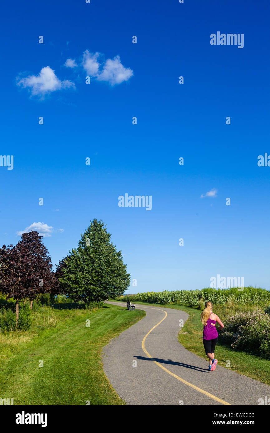 Female jogger on winding path with blue sky. Stock Photo