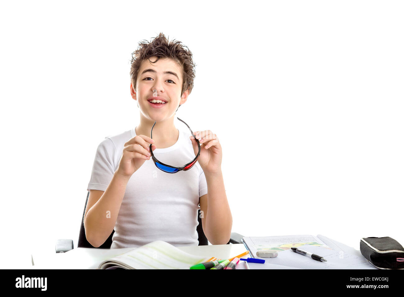 Caucasian smooth-skinned boy holding black plastic 3D Cinema eyeglasses with both hands while doing  homework Stock Photo