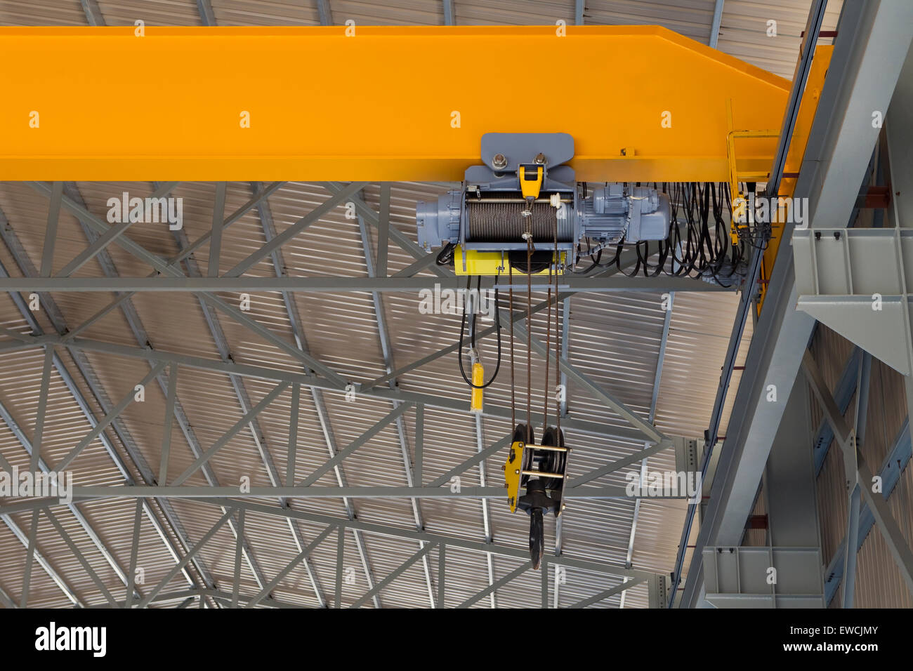 Close up of an indoor factory overhead crane on a yellow beam Stock Photo
