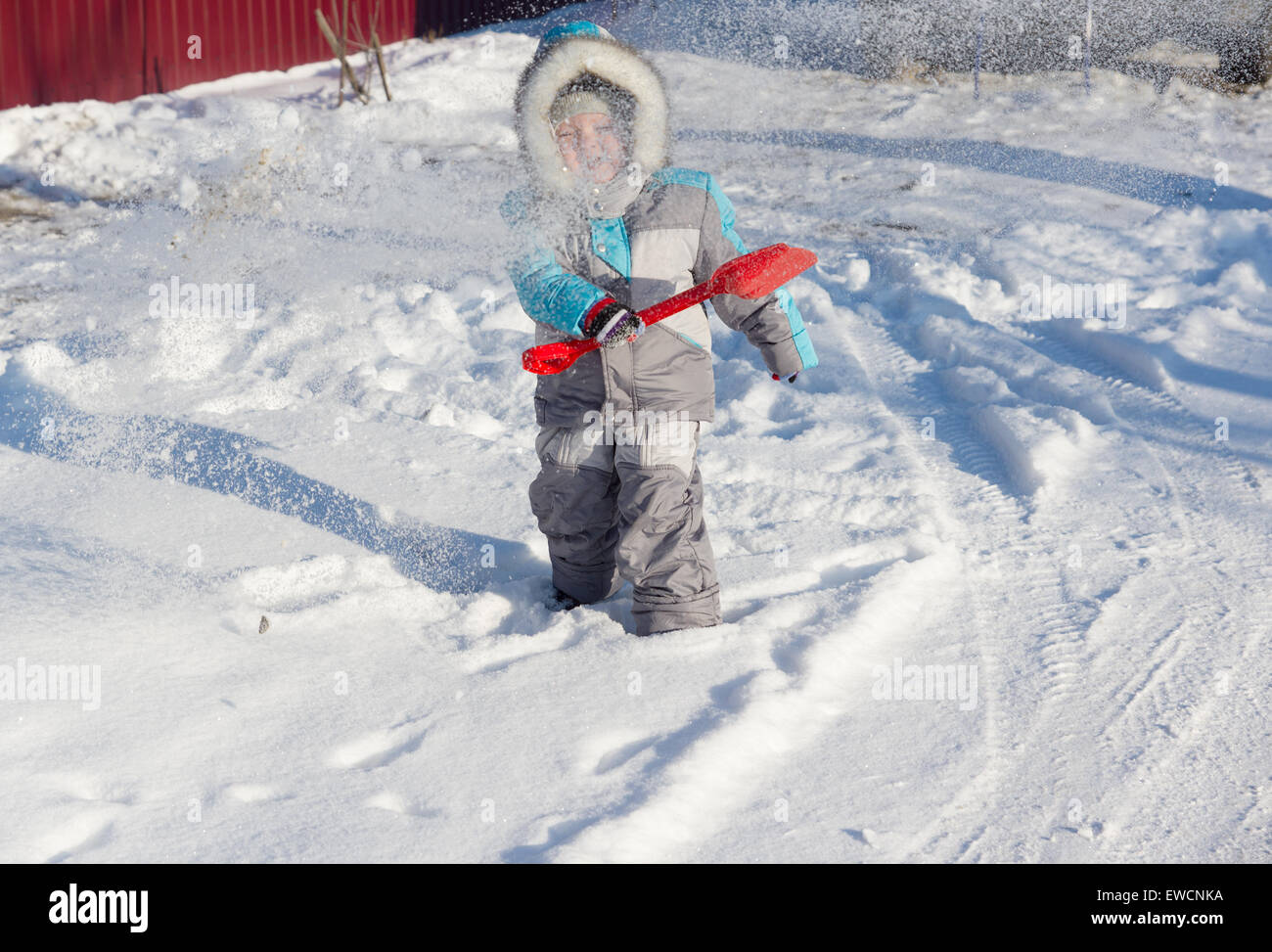 warmly dressed in overalls boy playing outdoors in snowy winter Stock Photo
