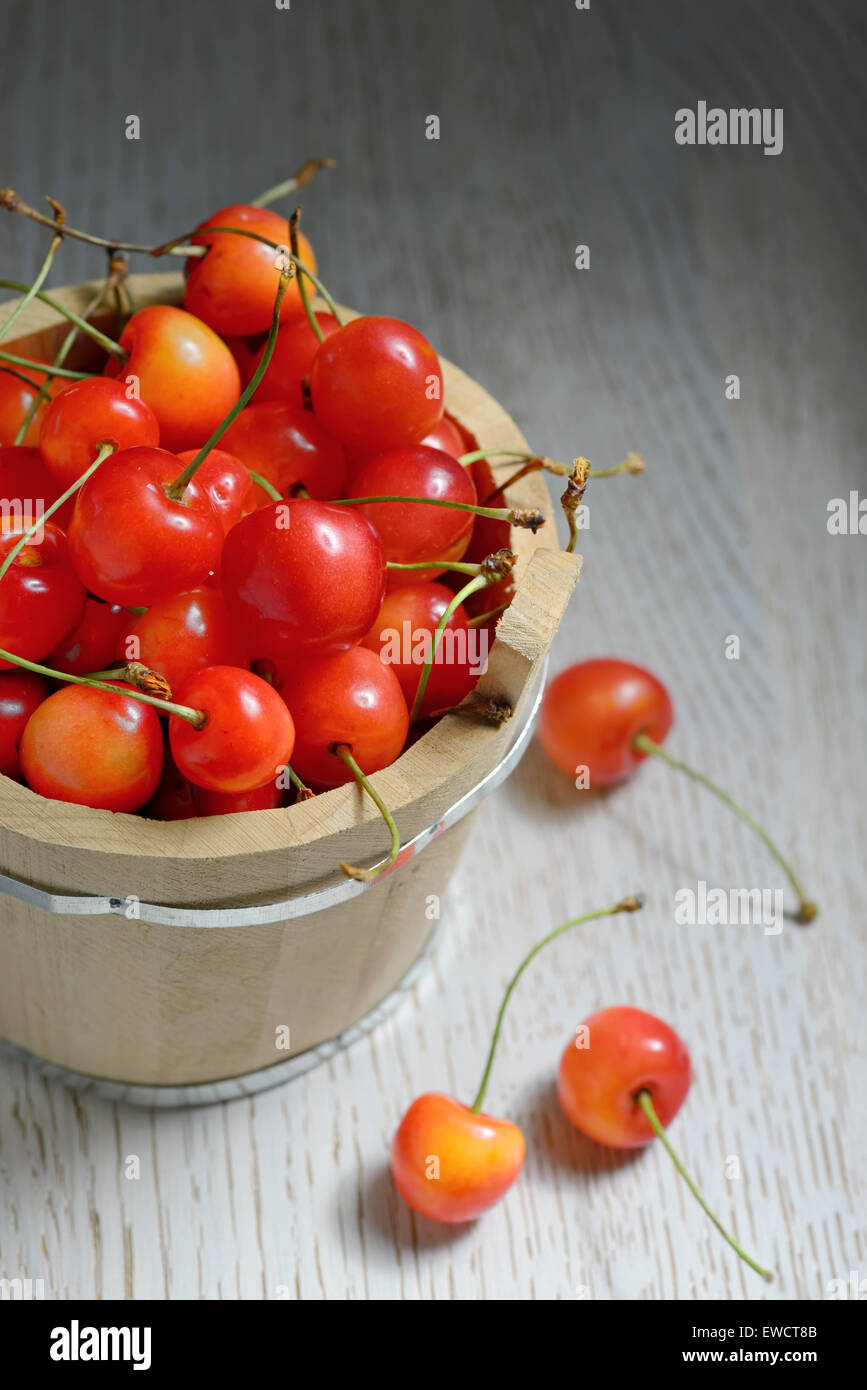 Sweet Cherries in Bucket on Wooden background Stock Photo