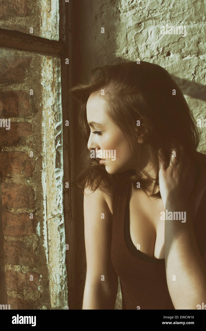 Beautiful young pensive woman looking out of the window Stock Photo