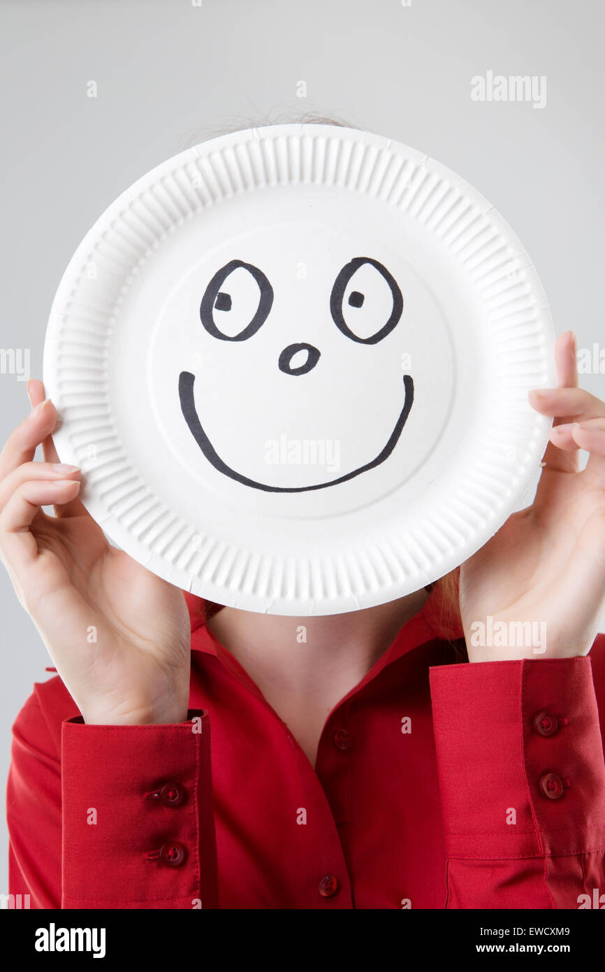 business woman holding a paper plate up to her face with a happy face drawn  on plate Stock Photo - Alamy
