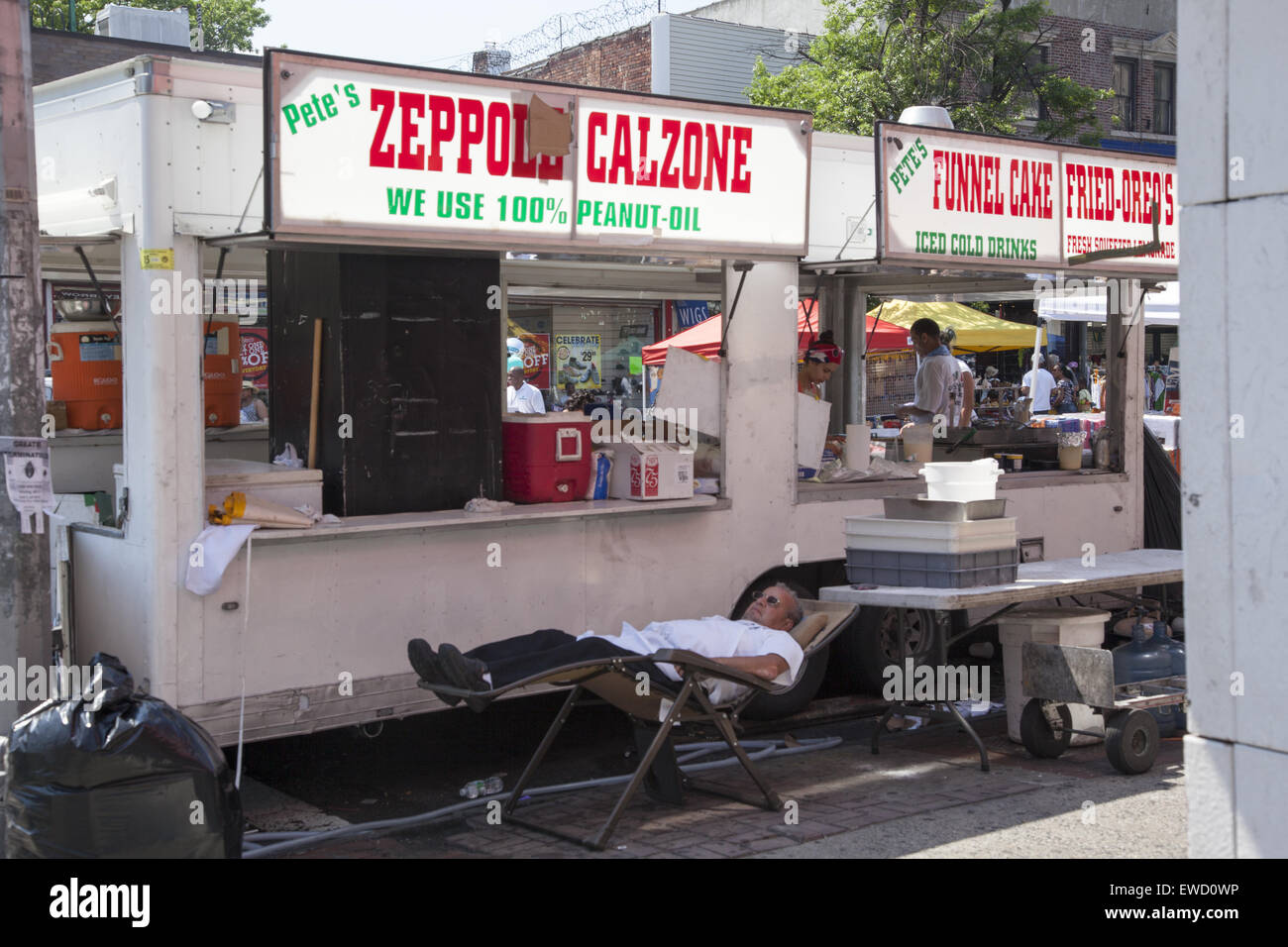 Food vendor takes a snooze behind his concession at a street festival along Flatbush Avenue in Brooklyn, NY. Stock Photo