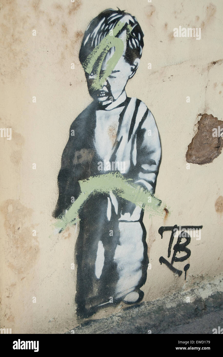 Editorial image of Urban artwork of a small boy possibly by Street artist Banksy, which ironically has been defaced by graffiti. Stock Photo