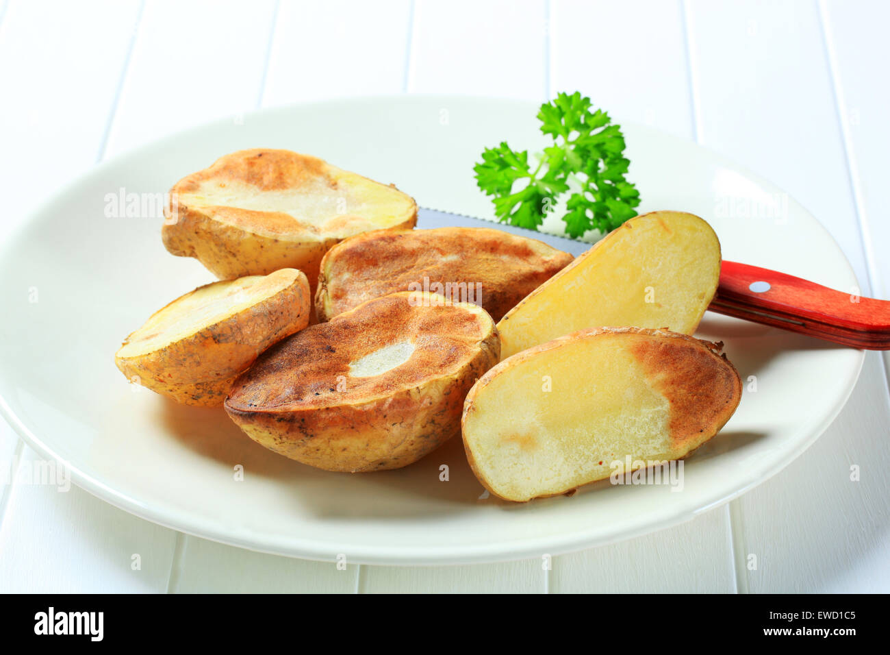 Halved oven-roasted potatoes on plate Stock Photo