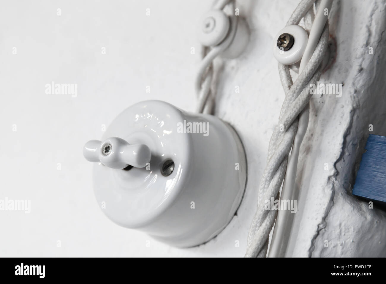 Vintage white ceramic electric switch with turning key mounted on the wall Stock Photo