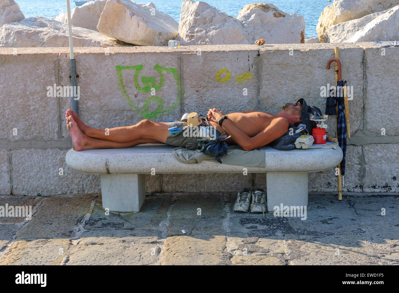 A young man asleep on a concrete bench. Piran. Slovenia, Stock Photo