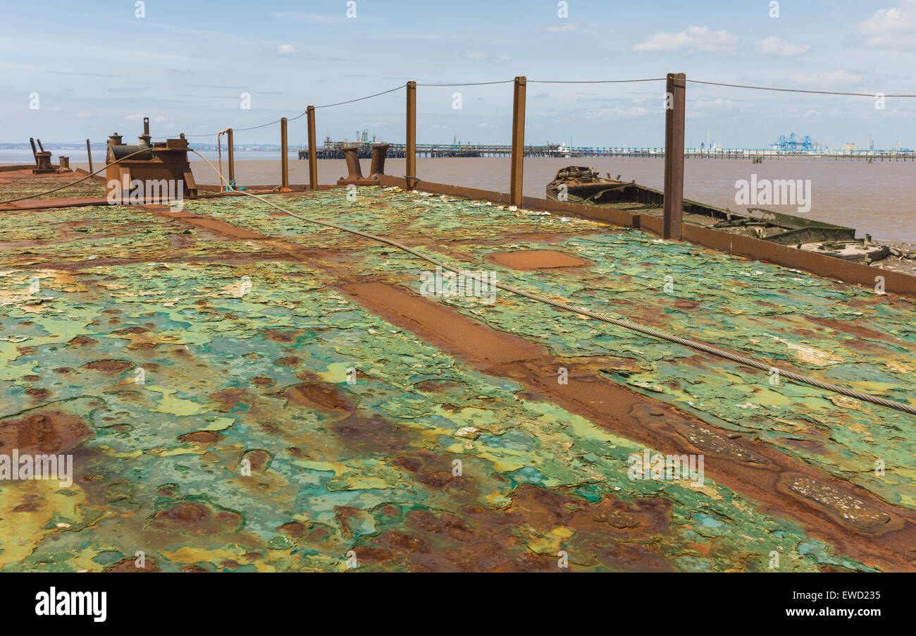 Rusting, derelict, ship deck overlooking the mud bank of the Humber estuary and other derelict boats and jetty. Stock Photo