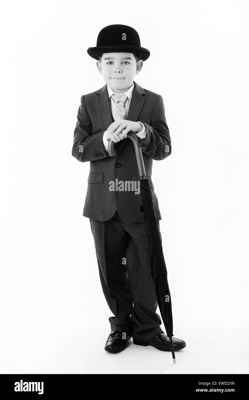 young boy pretending he's a business person wearing a suit and bowler hat holding a umbrella Stock Photo
