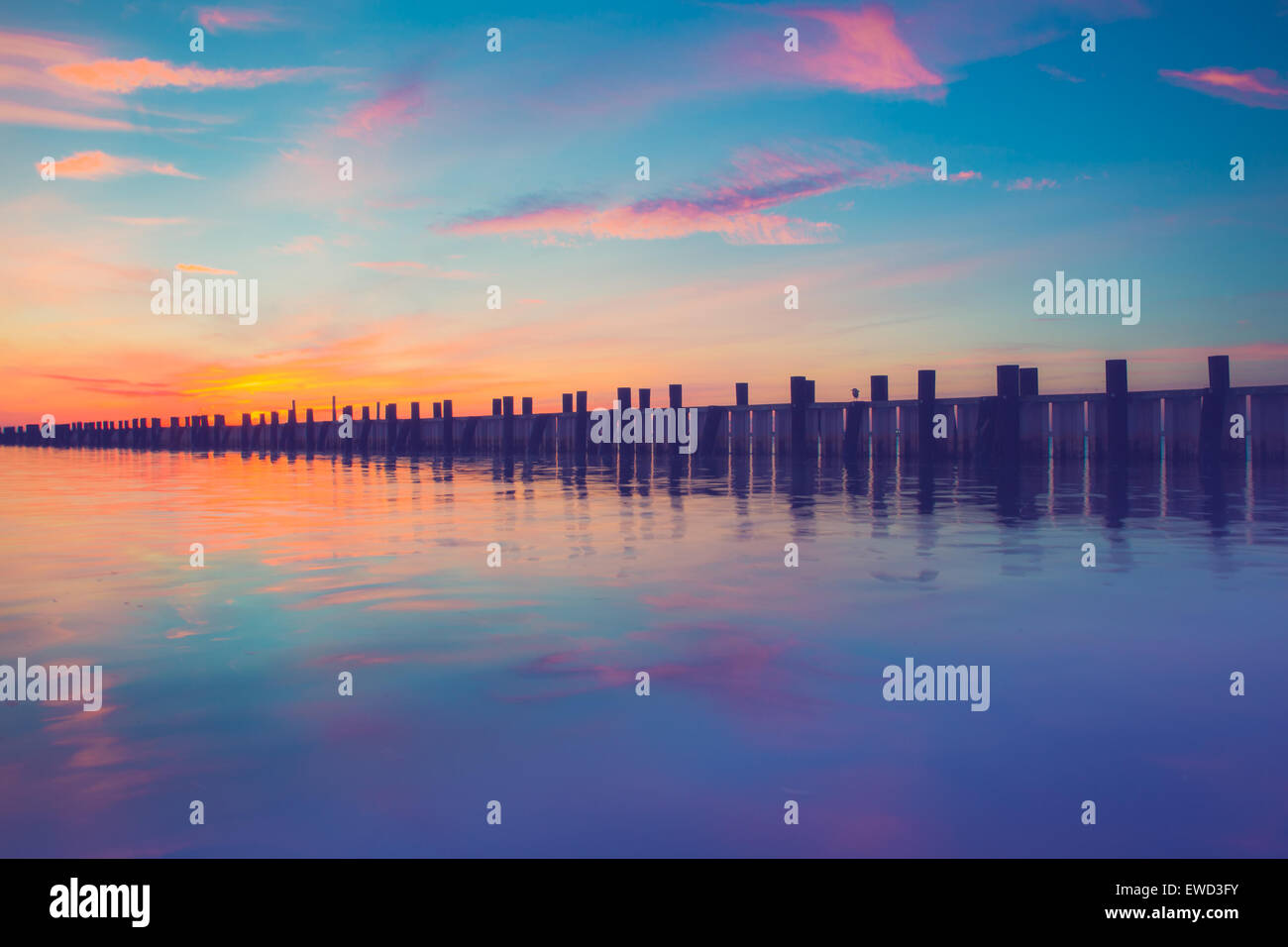 Beautiful ocean scene with wooden pier at sunset Stock Photo