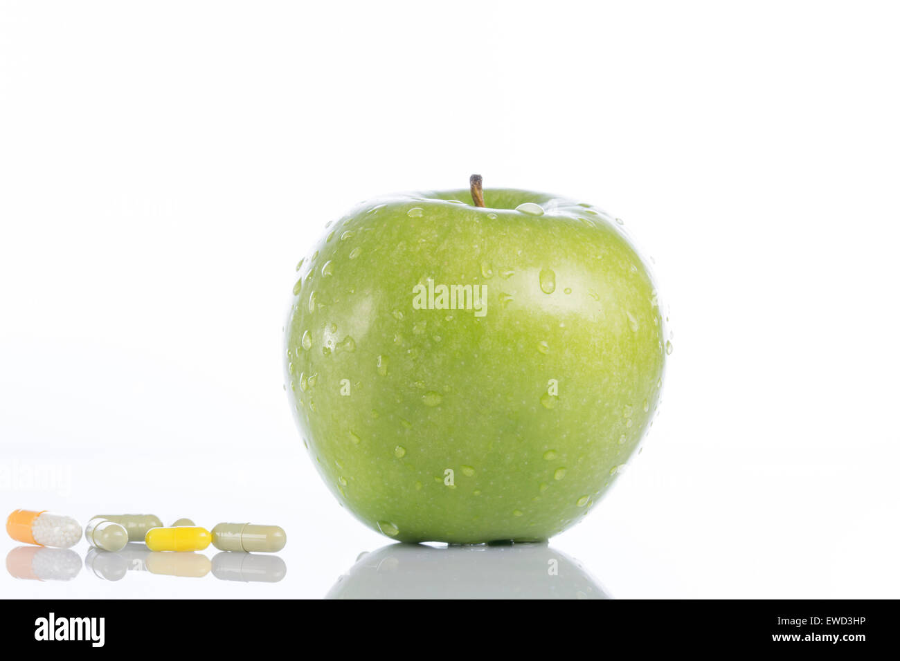 Natural green apple and various colored pills on white background Stock Photo