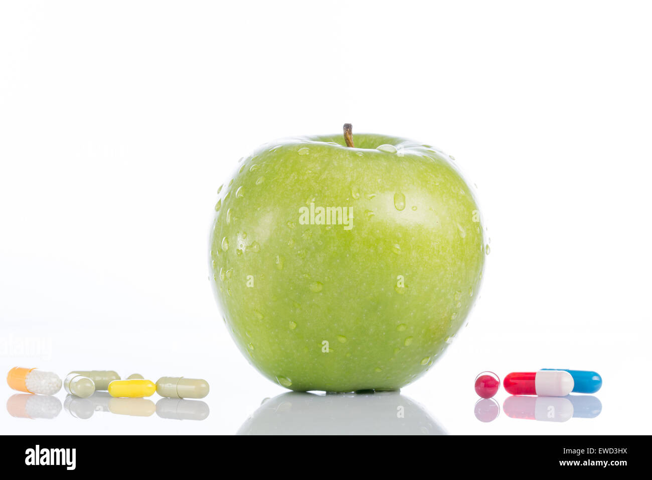 Green apple and various colored pills on white background Stock Photo