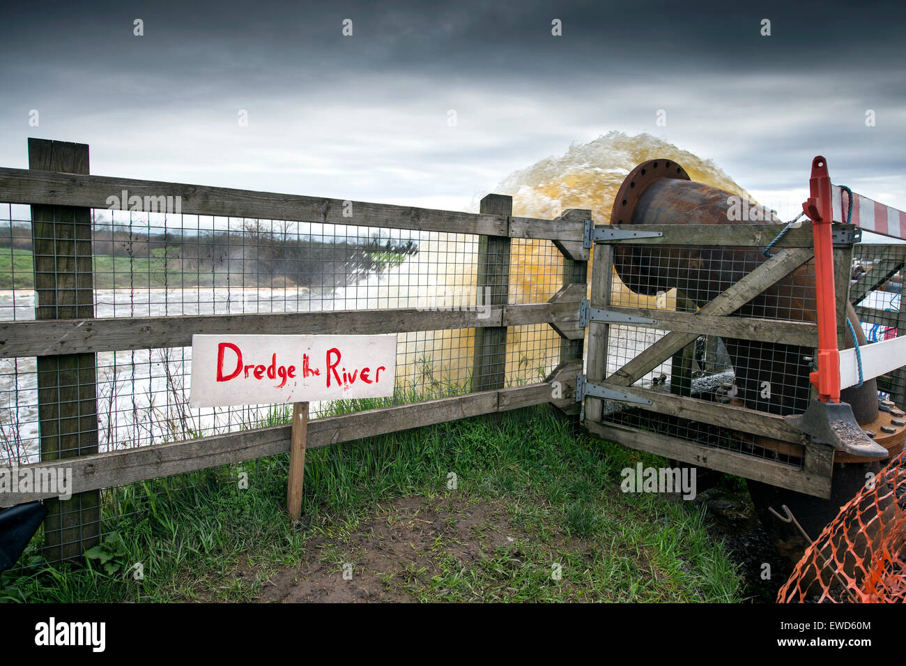 A 'Dredge the River' sign next to a pump outlet draining the flooded Somerset Levels into the River Parrett near Moorland Stock Photo