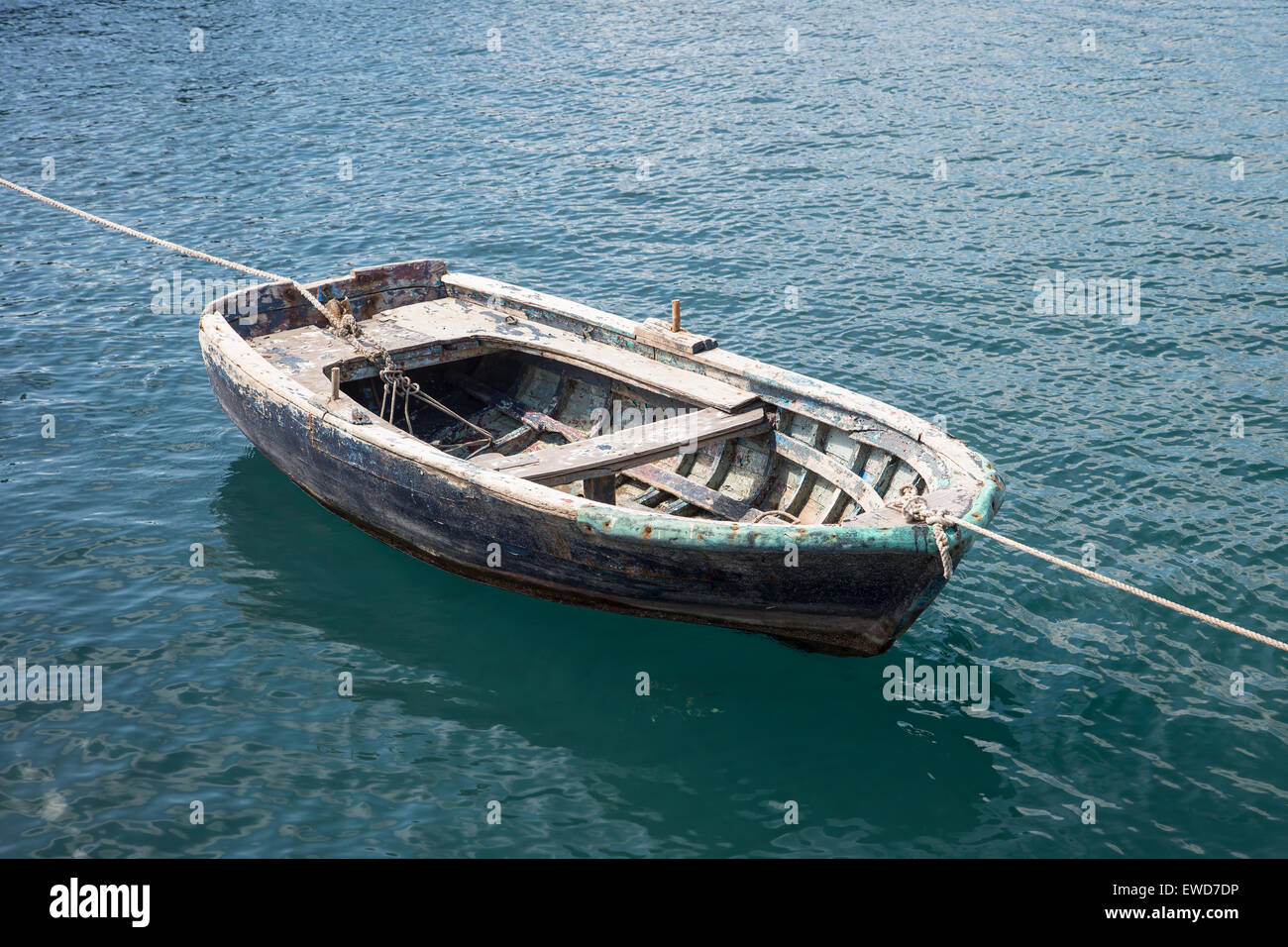 Old wooden rowing boat tied up in a harbor harbour in Turkey at both stern and bow Stock Photo
