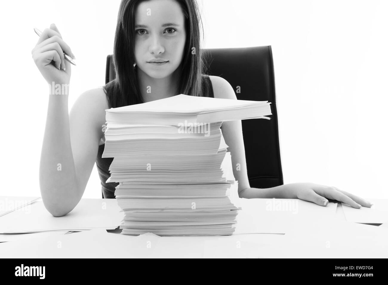 woman at a desk in the office with a very large stack of paper work in front of her Stock Photo