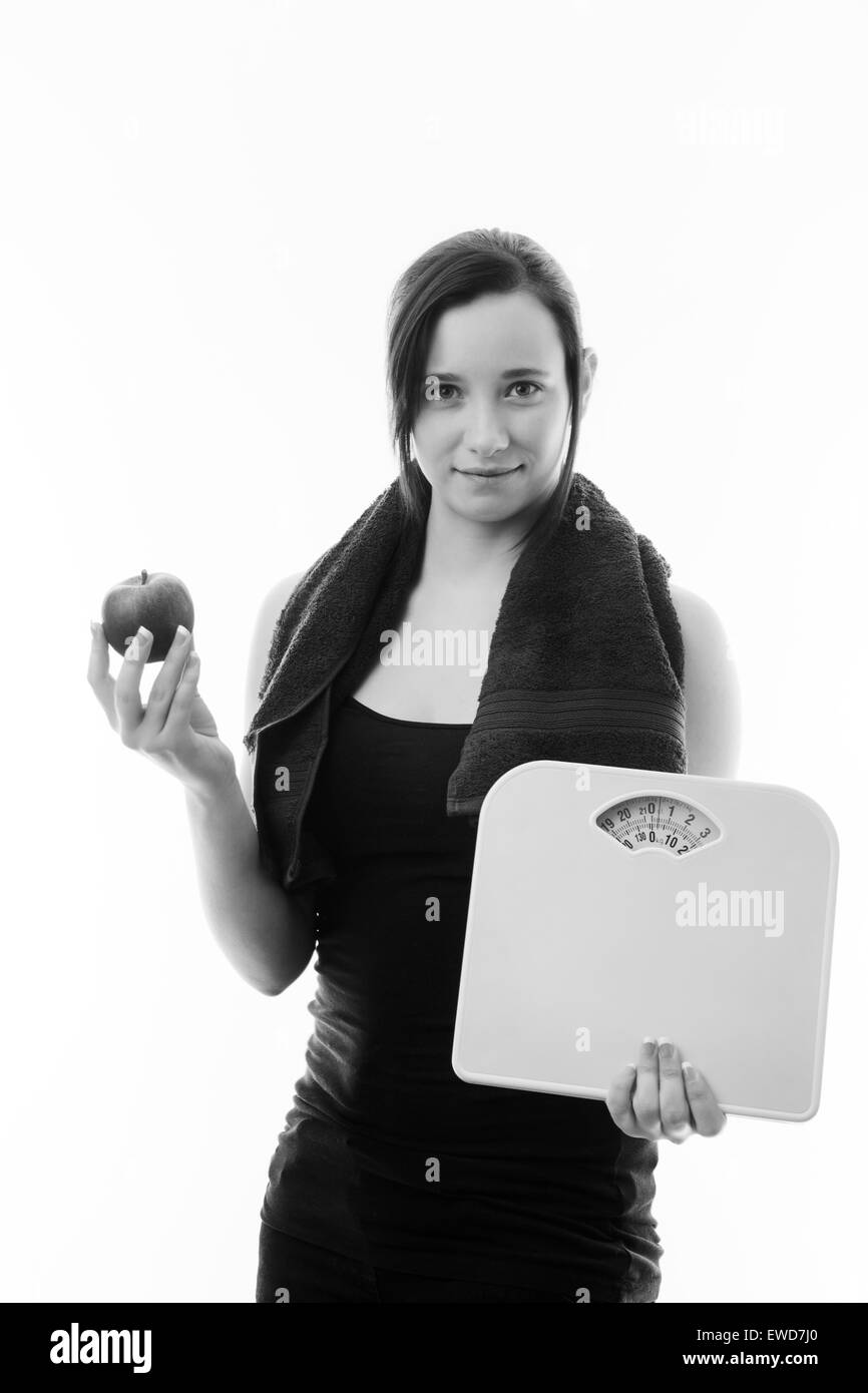young woman holding scales and a single apple watching her weight Stock Photo