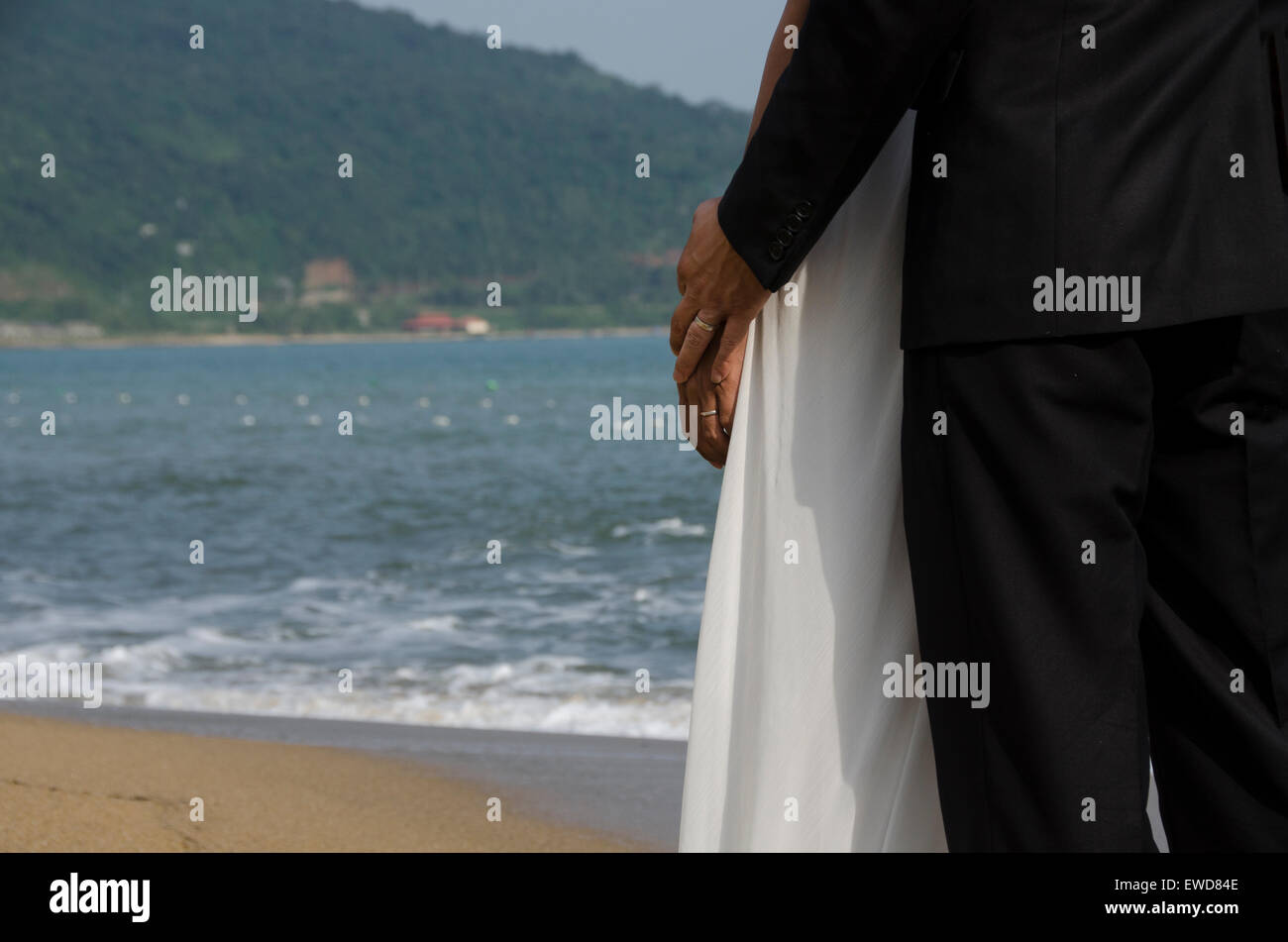 Lovers couple walking on beach wedding photo holding hands hugging laughing  Interracial couple Stock Photo
