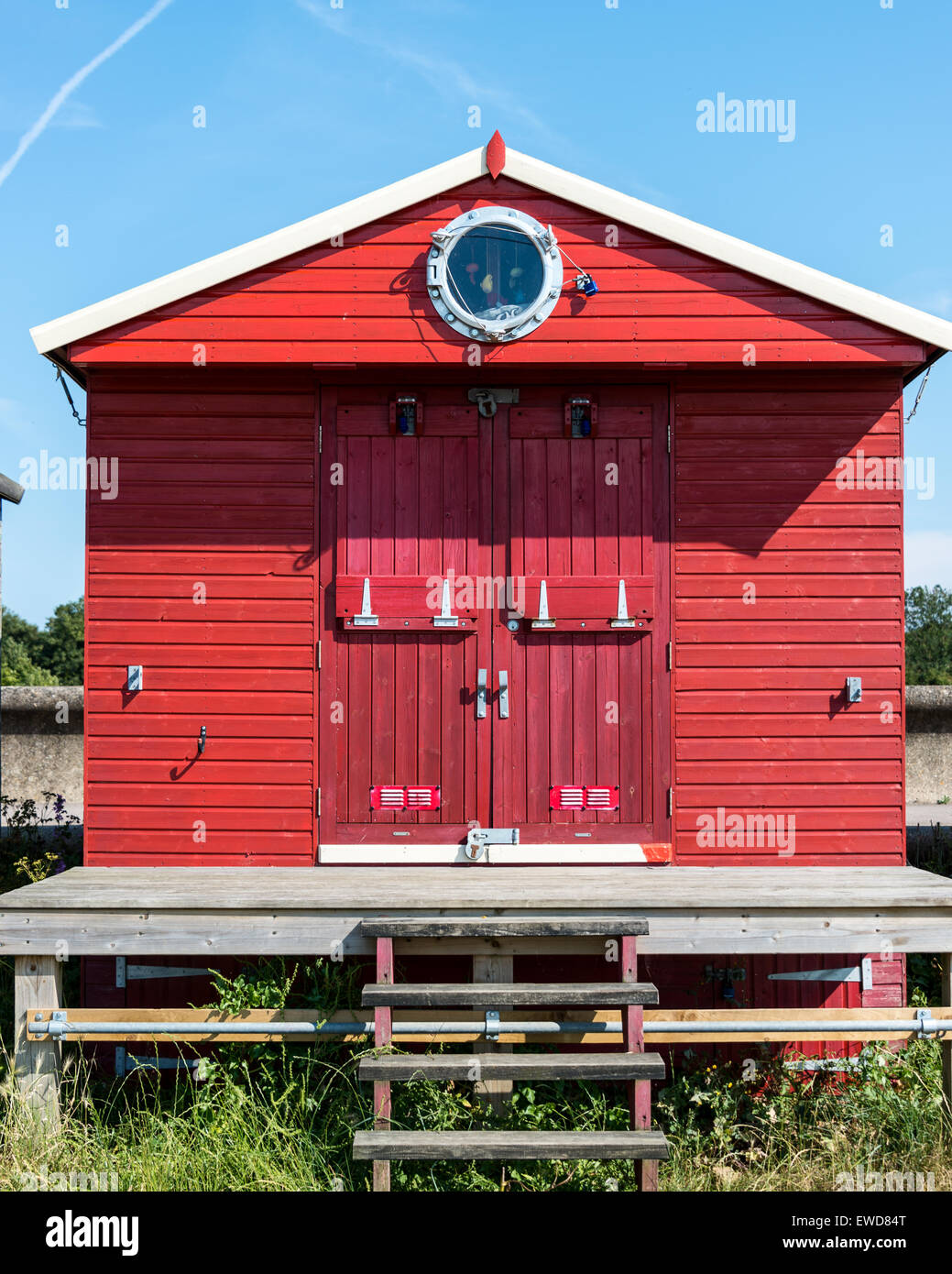 Red beach hut with porthole window Stock Photo