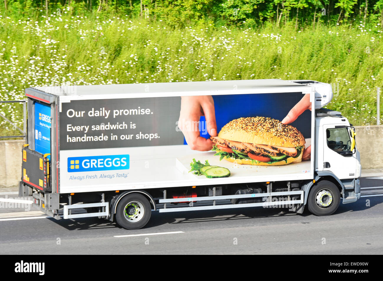 Greggs bakers stores supply chain food delivery lorry with advertising graphics along side of truck driving along English motorway England UK Stock Photo