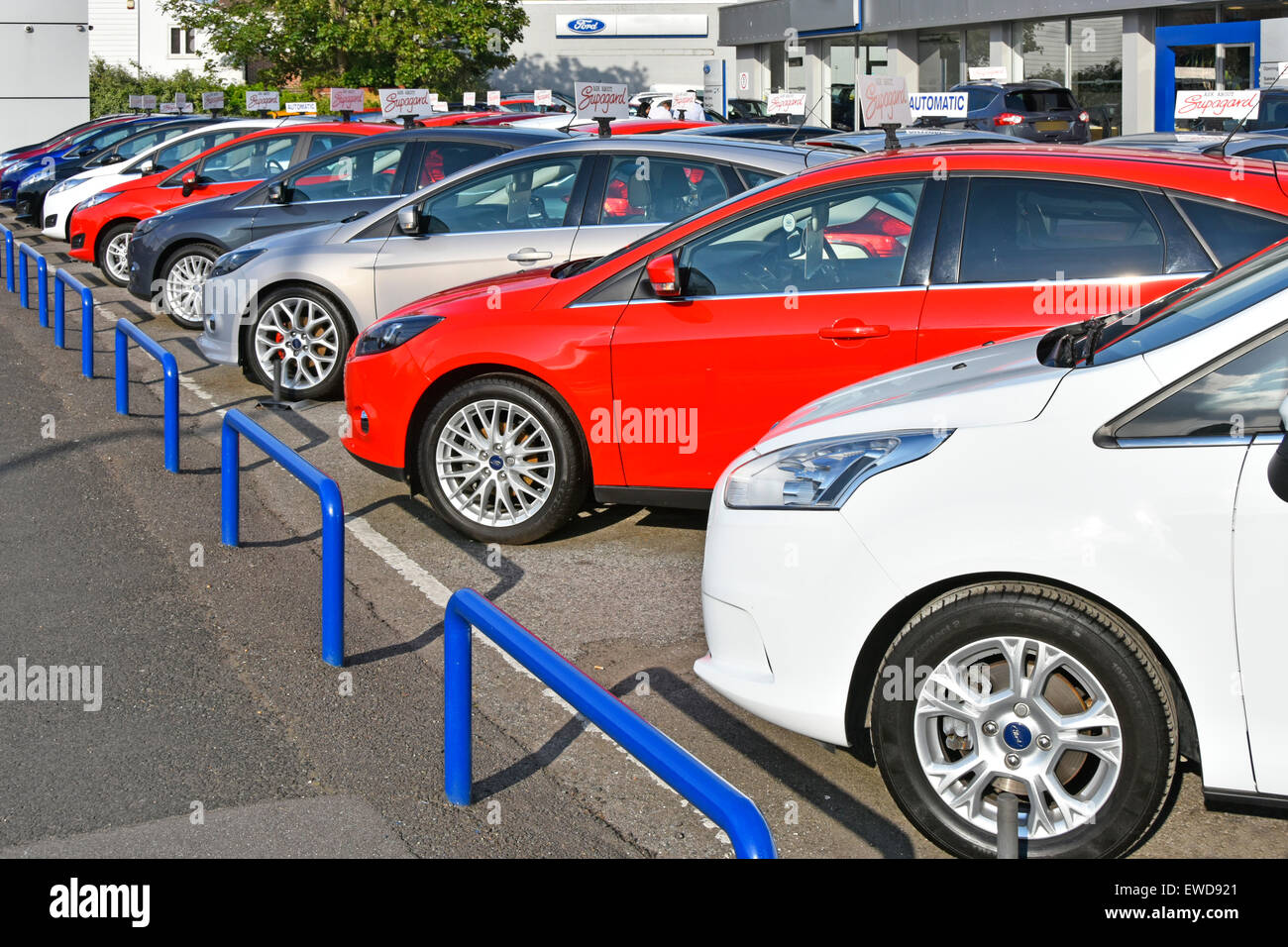 Ford car dealer business forecourt abutting pavement display of row of second hand cars for sale dealership name removed Brentwood Essex England UK Stock Photo